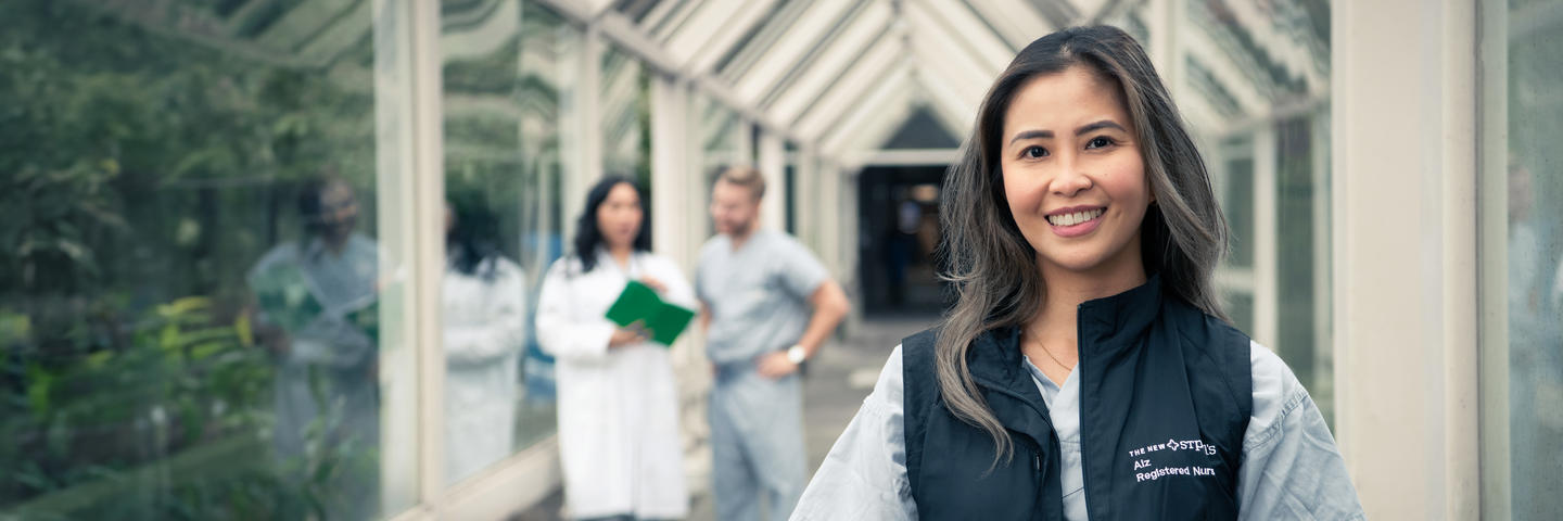 Nurse smiles pleasantly as her colleagues discuss a medical report