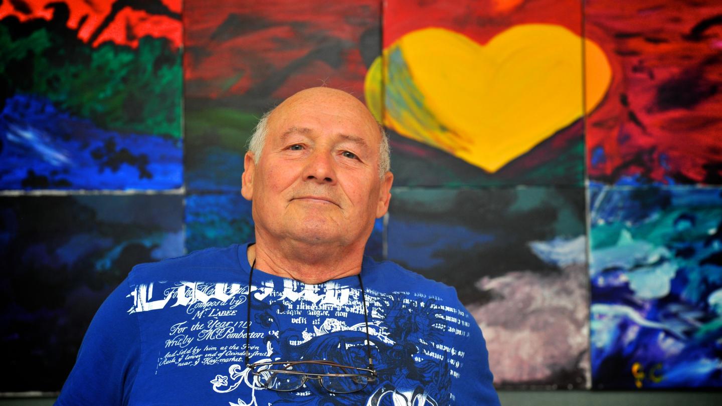 A man sits in front of a colourful wall