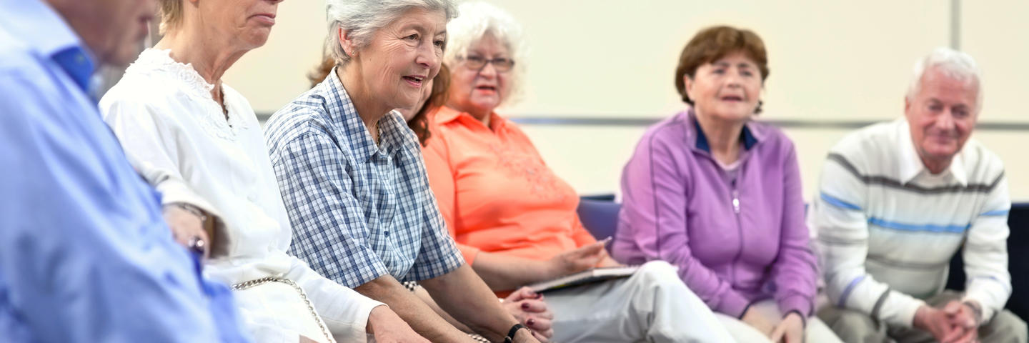 A group of older people sit in chairs in a half circle